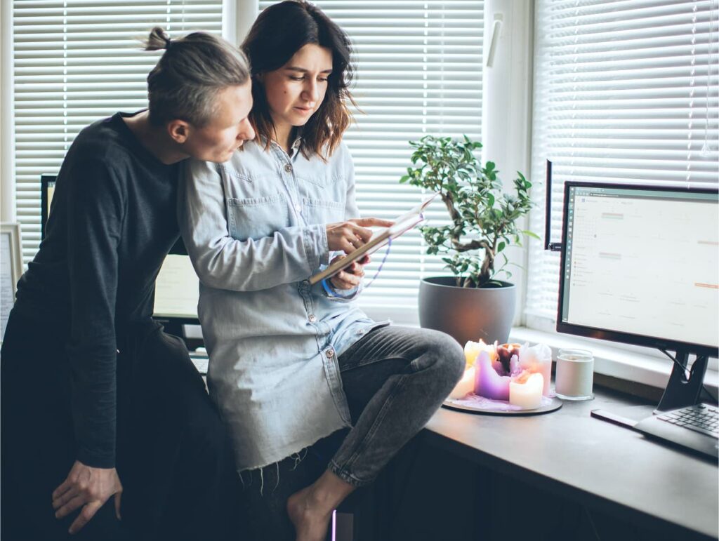 Para przeglądająca tablet w biurze przy komputerze.